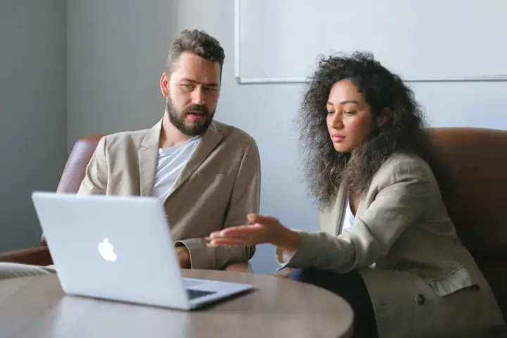 Un business developer y su colega analizan datos en una laptop.